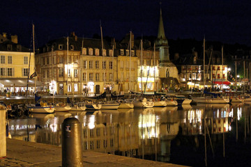 Fototapeta na wymiar Honfleur, France - July 10 2017: Honfleur harbour in Normandy by night, France. Color houses and their reflection in water