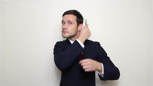 Young handsome businessman in a blue suit combing her hair and adjusts his suit, looking at the camera.Portrait on a white background.