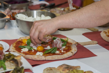Pizza Maker who Prepares a Delicious Pizza with Bacon and Cherry Tomatoes