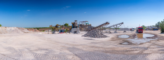 Crushing machinery, cone type rock crusher, conveying crushed granite gravel stone in a quarry open...