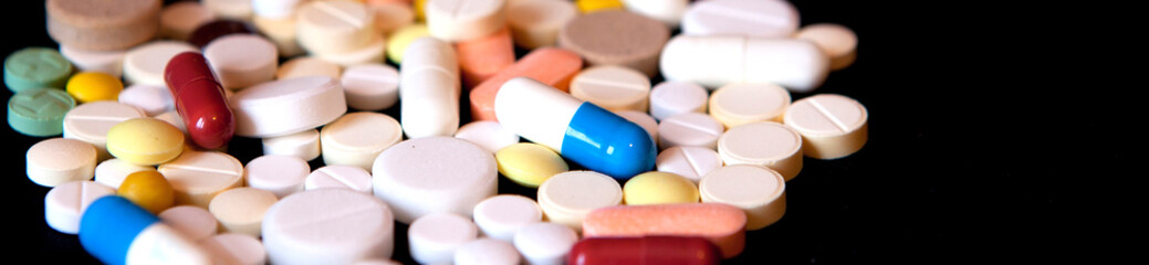 Pharmacy background on a dark table. Levitation pills. Tablets on a dark background which falling down. Pills. Medicine and healthy. Close up of capsules. Pills falling on black background