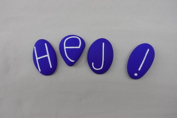 Hej ! Swedish text meaning Hello with a composition over white sand of blue colored stones