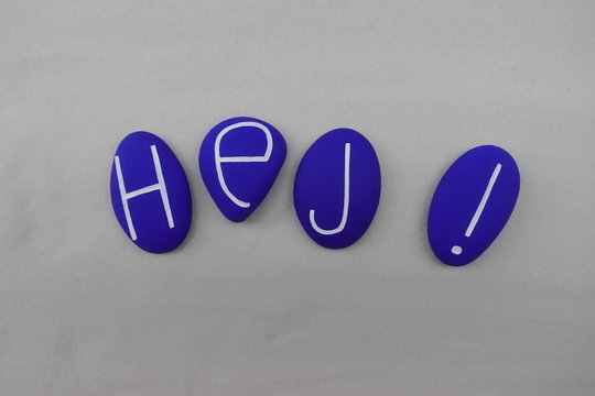 Hej ! Swedish text meaning Hello with a composition over white sand of blue colored stones