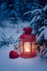 Christmas lantern under the tree with a heart in the woods. Christmas eve in the snowy forest