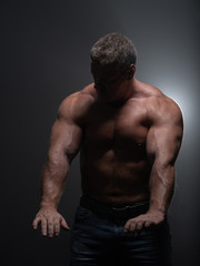 Powerful muscular bodybuilder posing on a black background. concept of strength and health