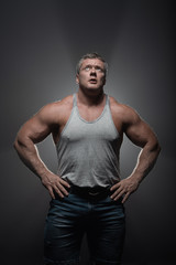 Fototapeta premium Powerful muscular bodybuilder posing on a black background. concept of strength and health