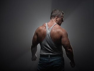 Fototapeta premium Powerful muscular bodybuilder posing on a black background. concept of strength and health