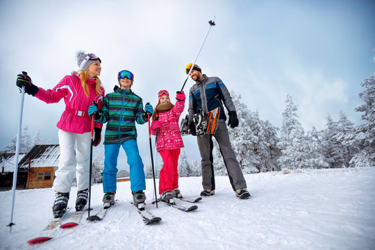 winter time and skiing - family with ski and snowboard on ski holiday in mountains