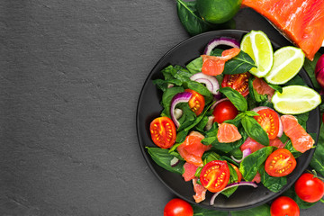 healthy food. salad with salmon, spinach, cherry tomatoes, red onion, lime and basil in black plate