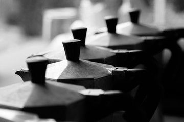 Closeup of lids of multiple Italian coffee stovetops in black and white.
