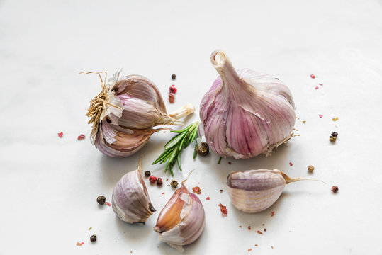 garlic with rosemary and peppercorn on white marble background. close up