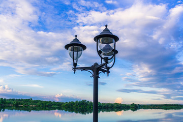Street lamp against the background of the river and sky