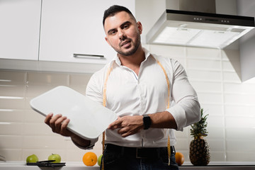 male dietitian holding scales in the kitchen. The concept of a healthy lifestyle