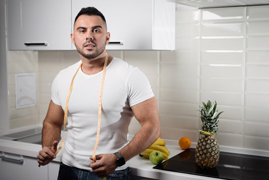 Male Dietitian In The Kitchen With A Measuring Tape Around His Neck. The Concept Of A Healthy Lifestyle