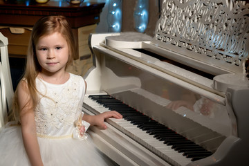 Little girl plays the piano by candlelight.