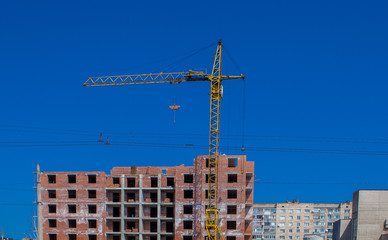 Construction site of a new apartment high building with tower cranes against blue sky. Residential area development. Real estate project growth concept