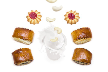 cashew falling into a glass of milk with splashes around which are tasty cookies