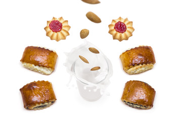 almond falling into a glass of milk with splashes around which are tasty cookies