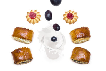 grape falling into a glass of milk with splashes around which are tasty cookies