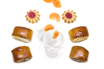 tangerine falling into a glass of milk with splashes around which are tasty cookies