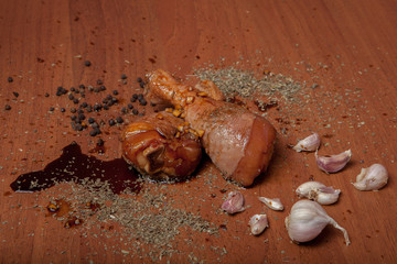 Chicken raw shrimp meat on a wood chipboard, spices for chicken, salt, roman, basil, garlic, pepper, soy sauce on a gray background
