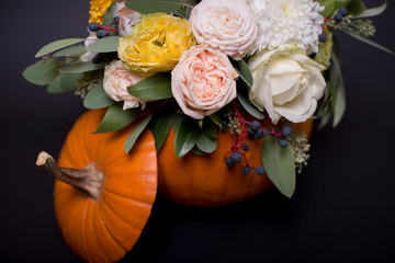 Autumn floral bouquet in pumpkin vase on black background, mix of flowers, peony rose, eucalyptus, chrysanthemum