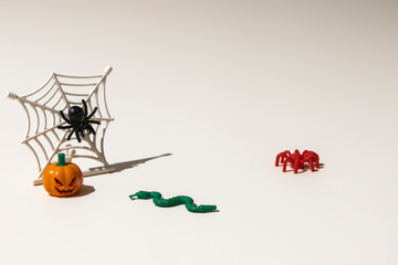 Composition of plastic toys for Halloween, with pumpkin, spider, cobweb, snake and bones