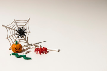 Composition of plastic toys for Halloween, with pumpkin, spider, cobweb, snake and bones