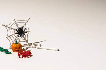 Composition of plastic toys for Halloween, with pumpkin, spider, cobweb, snake and bones