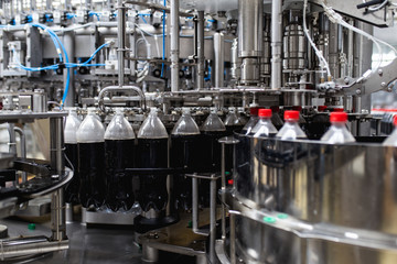 Bottling factory - Black juice bottling line for processing and bottling juice into bottles. Selective focus.