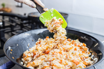  cooking pilau with vegetables. kitchen appliance, heat resistant rubber spatula.
