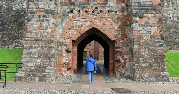 Carlisle Castle England woman walks through arch entry. The Cathedral Church of the Holy and Undivided Trinity. Cumbria, North West England. Founded as an Augustinian priory.