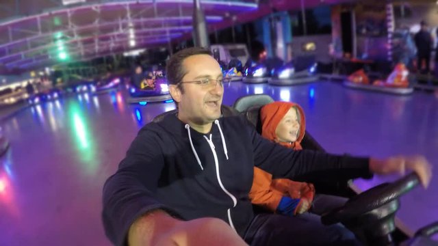 Father and son at amusement park attraction, night roller coaster