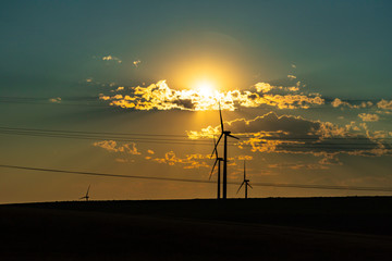 Obraz premium Glowing sun over wind turbines