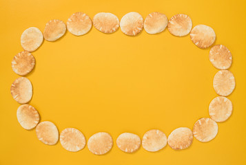 Frame made of mini pita bread on yellow background