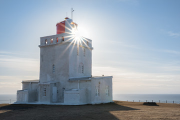 Sunburst shining through the Dyrholaey Lighthouse in Iceland with the Atlantic Ocean in the background