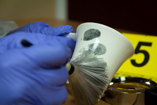 Forensic expert finds fingerprints on the cup of coffee. Crime scene