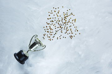 Golden trophy and stars confetti on gray cement background. sport achievement, success concept....