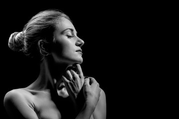 beautiful female profile with bare shoulders on black background with copy space, monochrome