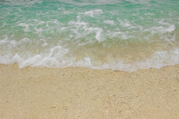 Fototapeta na wymiar Close up of sea wave rolling into the white sand. 