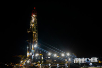 Oil and Gas Drilling Rig onshore dessert with dramatic cloudscape. Oil drilling rig operation on...