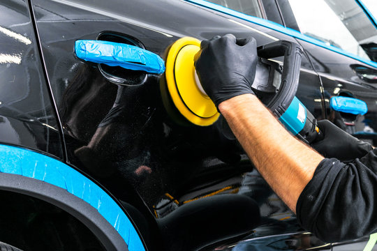 Car Polish Wax Worker Hands Applying Protective Tape Before Polishing. Buffing And Polishing Car. Car Detailing. Man Holds A Polisher In The Hand And Polishes The Car