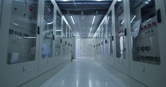Observing view of white corridor of operation center of solar power station with rows of electrical equipment