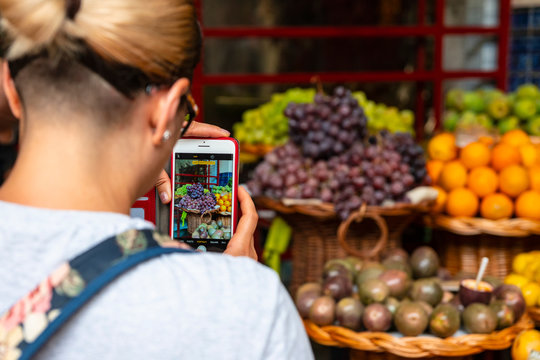 Phone in the hand of a girl with a photo of fruit. Selective focus.
