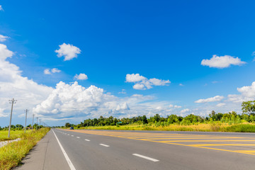 The asphalt road runs along the field and has a beautiful blue sky.