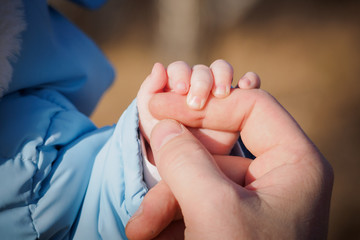 baby's little hand is holding dad's thumb