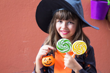 girl dressed up as a witch with candies and pumpkin. Halloween