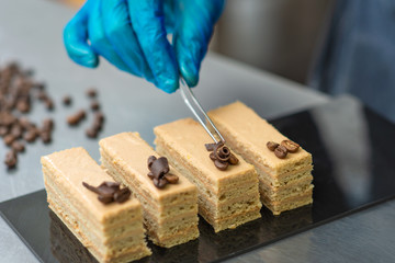 Pastry chef making coffee cakes , wearing gloves and decorating with the coffee beans 