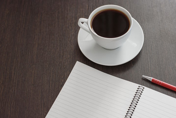 Obraz na płótnie Canvas Notebook with pen and cup of coffee on brown wooden table