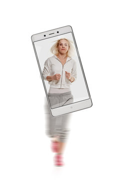 Portrait of young sporty woman running on white background. conceptual image with a smartphone, demonstration of device capabilities